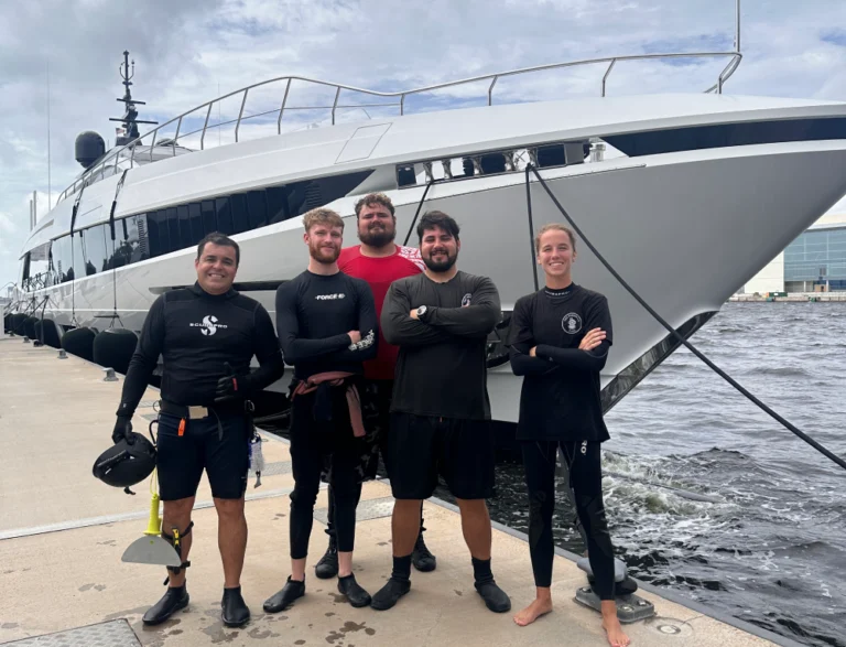 Barnacle King divers stand on the dock in front of a cleaned vessel in Palm Beach