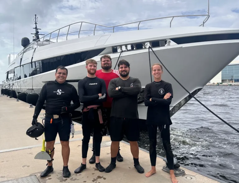 Barnacle King divers stand on the dock in front of a cleaned vessel in Palm Beach
