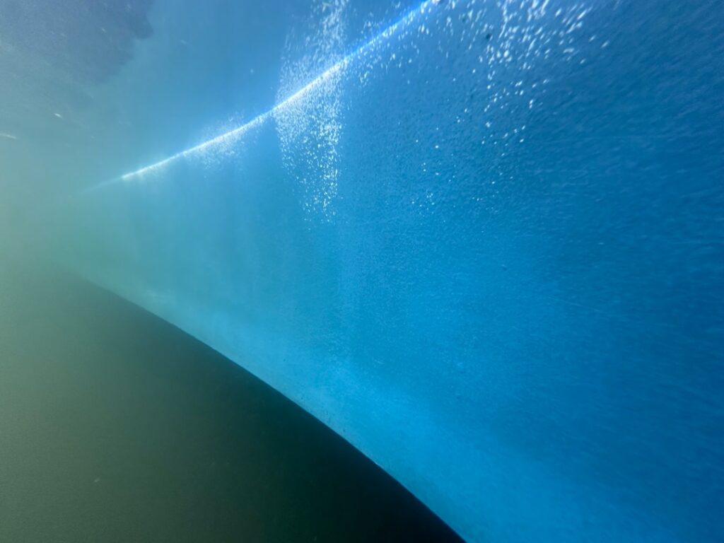Underwater view along a cleaned boat hull below the waterline